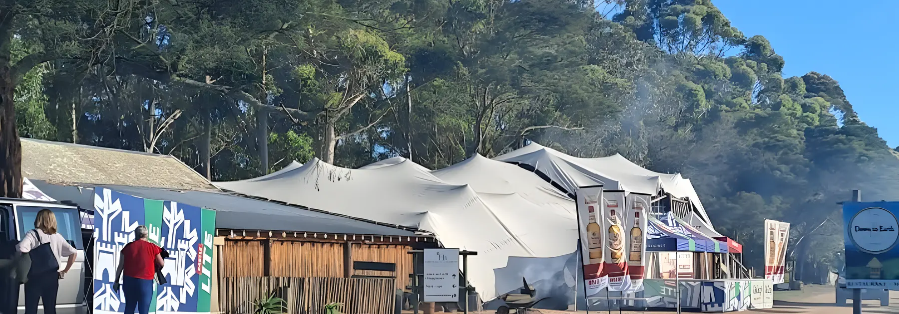 The Bush Lapa from outside: a timber building with white stretch tents under tall trees