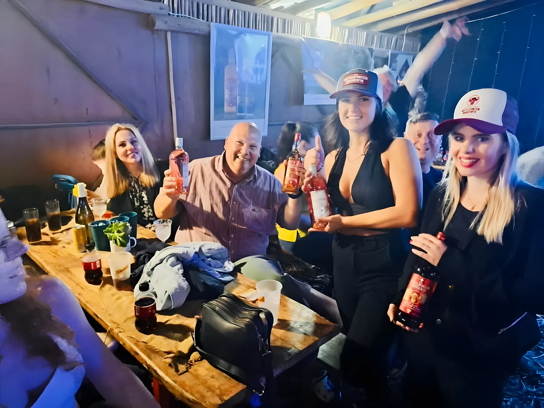 A group of friends at a table, smiling and raising their drinks for the camera